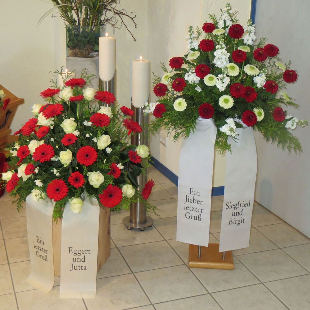 Trauergestecke mit weißen und roten Blumen